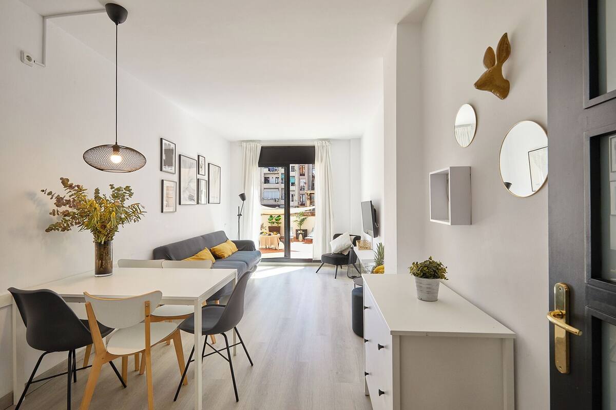 Una sala moderna con un sofá, una mesa de comedor, sillas y una zona de cocina.