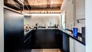 A modern kitchen with a wooden ceiling, black cabinetry, and a central island. - Exclusive apartment in the former Ospizio delle Donzelle, near Biennale Gardens (Venezia)