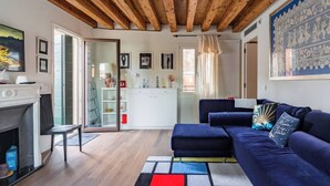 A modern living room with a fireplace, a blue sofa set, and a wooden ceiling. - Exclusive apartment in the former Ospizio delle Donzelle, near Biennale Gardens (Venezia)