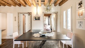A dining area with a dark table, white chairs, and a decorative centerpiece. - Exclusive apartment in the former Ospizio delle Donzelle, near Biennale Gardens (Venezia)