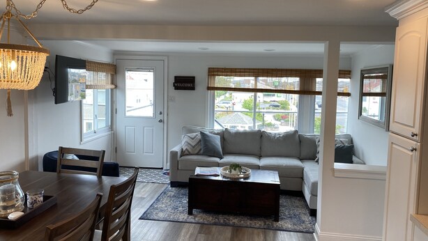 A living room with a sofa, coffee table, and dining area with chairs and a table.