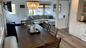 A modern kitchen with a wooden dining table, white cabinets, and a chandelier.