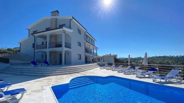 Un bâtiment à deux étages doté d’une piscine et de chaises longues.
