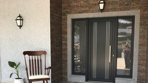 Une entrée moderne avec une porte noire, une chaise en bois et des carreaux de sol à motifs.