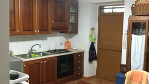 Une cuisine de taille réduite, avec des meubles de rangement en bois, une cuisinière à gaz et un évier.