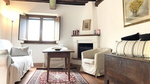 Una sala de estar acogedora con chimenea, un sofá, una mesa y una alfombra estampada.