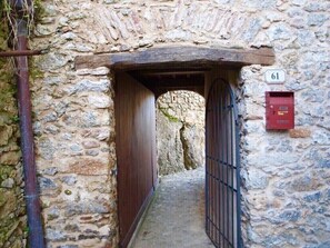 A narrow stone corridor with a wooden door and a metal gate, leading to a stone wall with a mailbox. - Delightful house with sea view on the hills of Camaiore
LAST MINUTE DISCOUNT 10% (Camaiore)