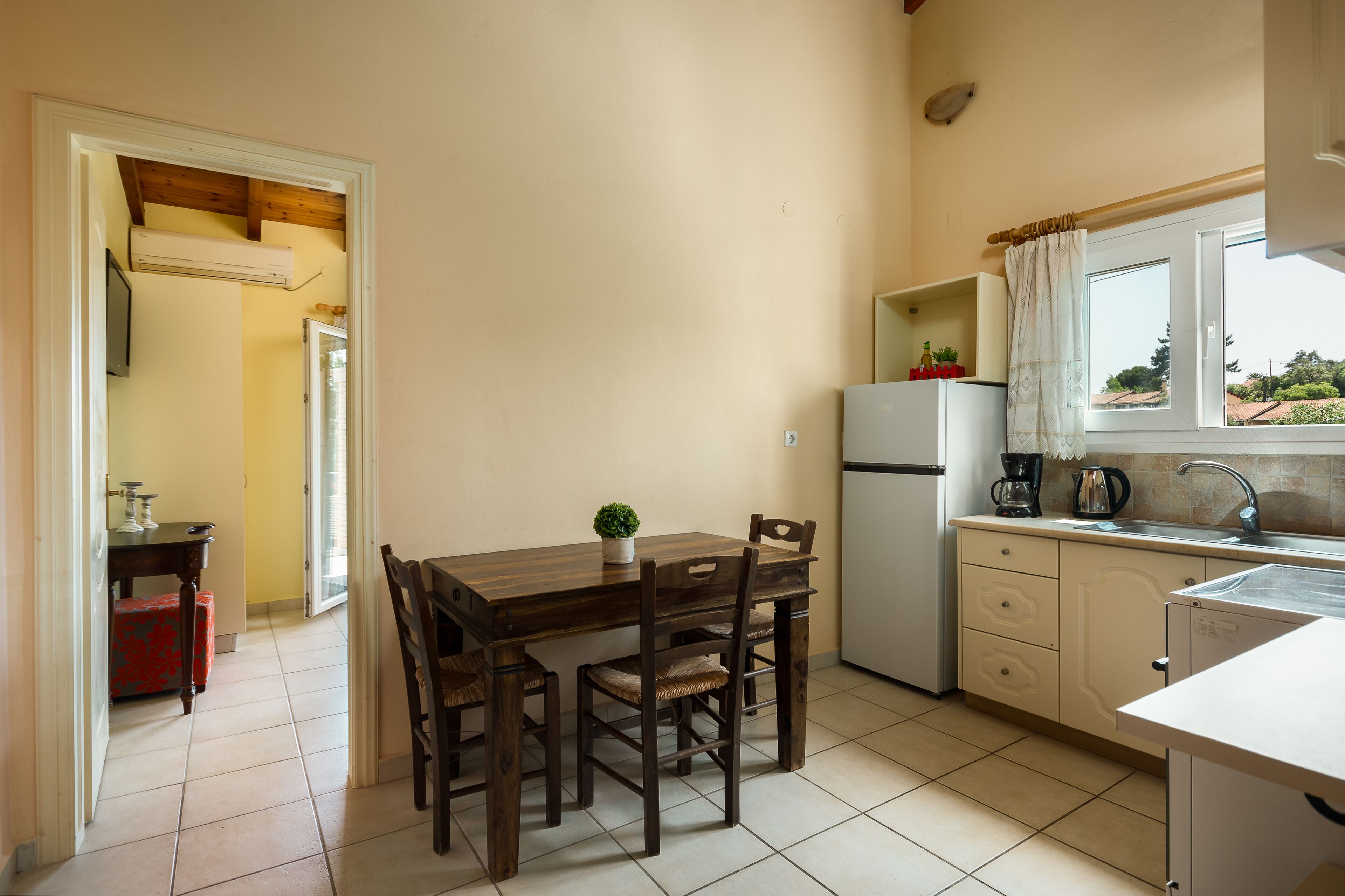 A compact kitchen with a dining table and chairs, a refrigerator, and a window with a view.