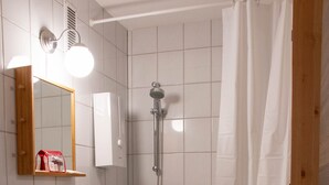 A bathroom with a white sink, a mirror, a shower, and a toilet. - LuPartment-Studio-Apartment-Stadtmitte (Ludwigshafen)