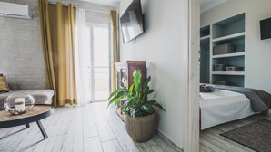 Een moderne kamer met een bed, een televisie, een plant en een bank.