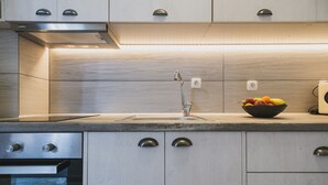 Een moderne keuken met een roestvrijstalen afzuigkap, een inbouwoven en een schaal fruit op het aanrecht.