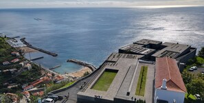 Ein Küstenblick mit einem modernen Gebäude, das einen Dachgarten und einen Museumseingang zeigt.