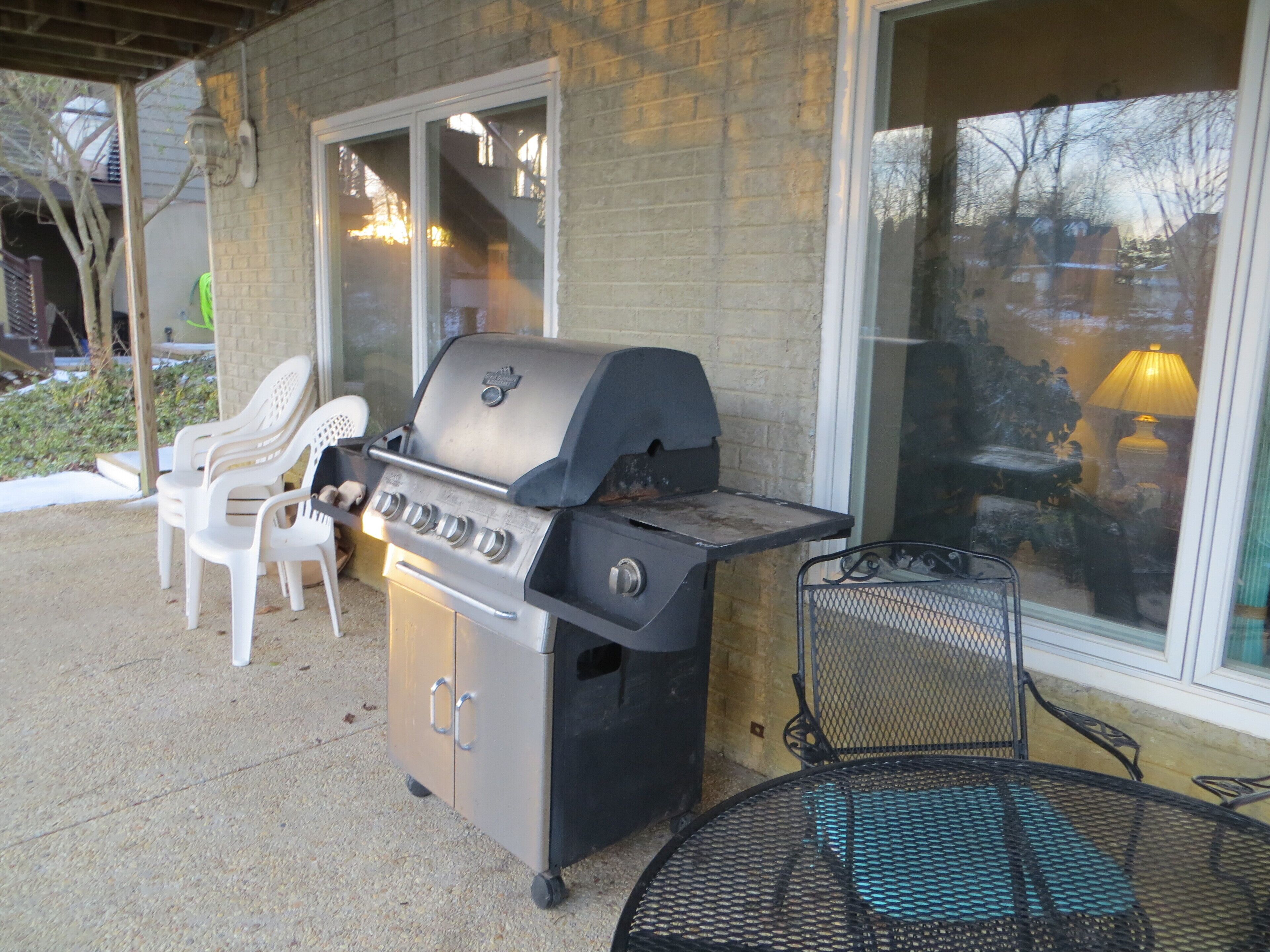 Patio esterno con barbecue, tavolo e sedie.
