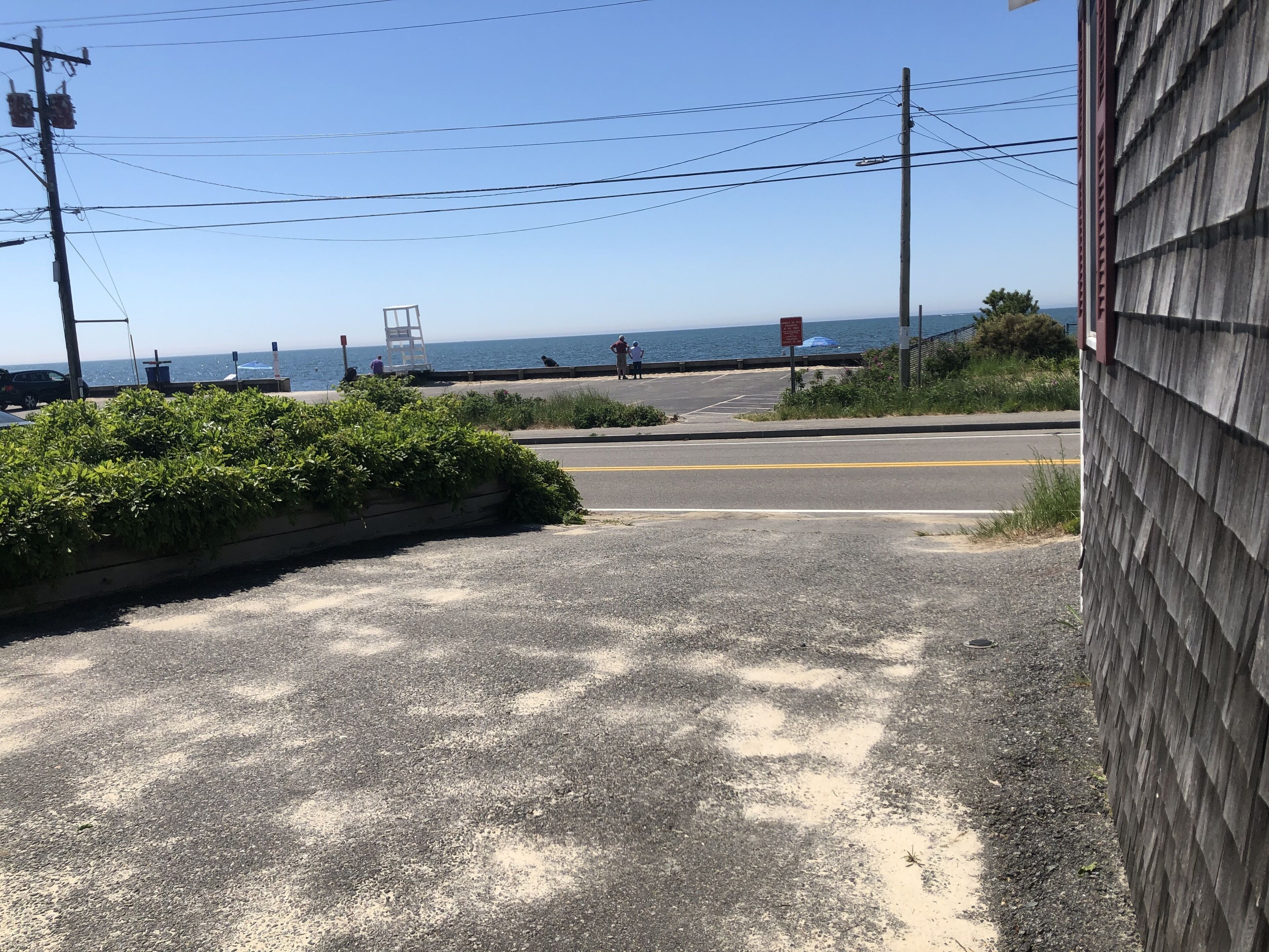 Uma estrada costeira com vista para o oceano, um passeio para pedestres e um edifício de madeira.
