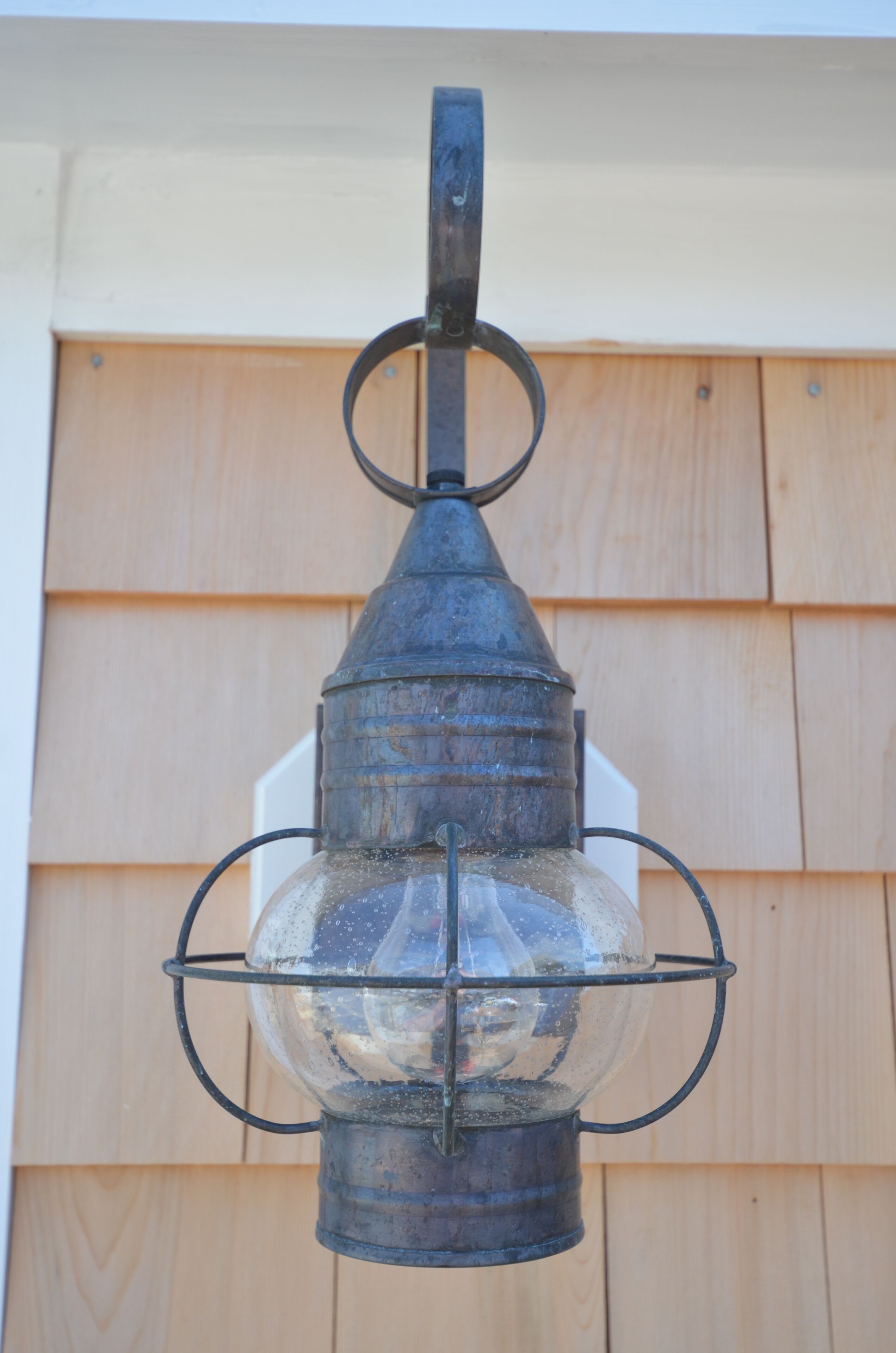 Une lanterne en métal dotée d’un boîtier en verre, fixée à un mur.