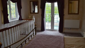 Ein Schlafzimmer mit einem großen Bett, einer Holztreppe, einem Heizkörper und einem Fenster mit Vorhängen.