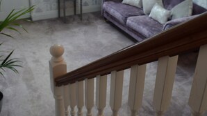 Ein Wohnzimmer mit einem violetten Sofa, einem kleinen Tisch und einer Treppe mit weißen Spindeln.