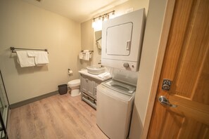 Un baño pequeño con inodoro, lavadora y lavamanos.