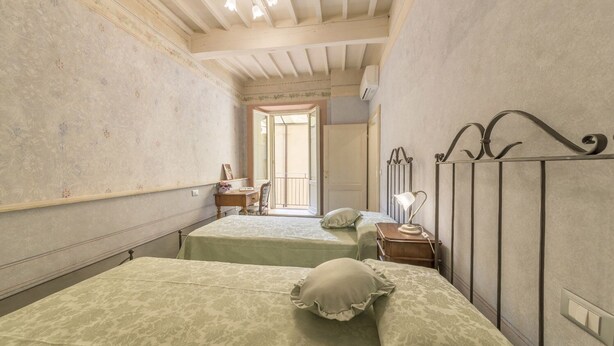 Een kleine kamer met twee bedden, een bureau en een stoel.