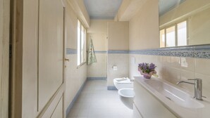 Een badkamer met toilet, wastafel en spiegel.
