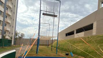 Uma área de ginástica ao ar livre com parede de escalada, quadra de basquete e piscina.
