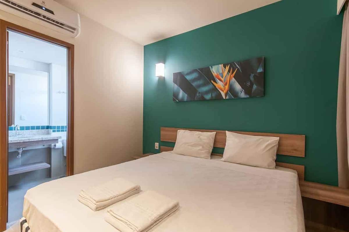 Een hotelkamer met een bed, een schilderij aan de muur en een raam.