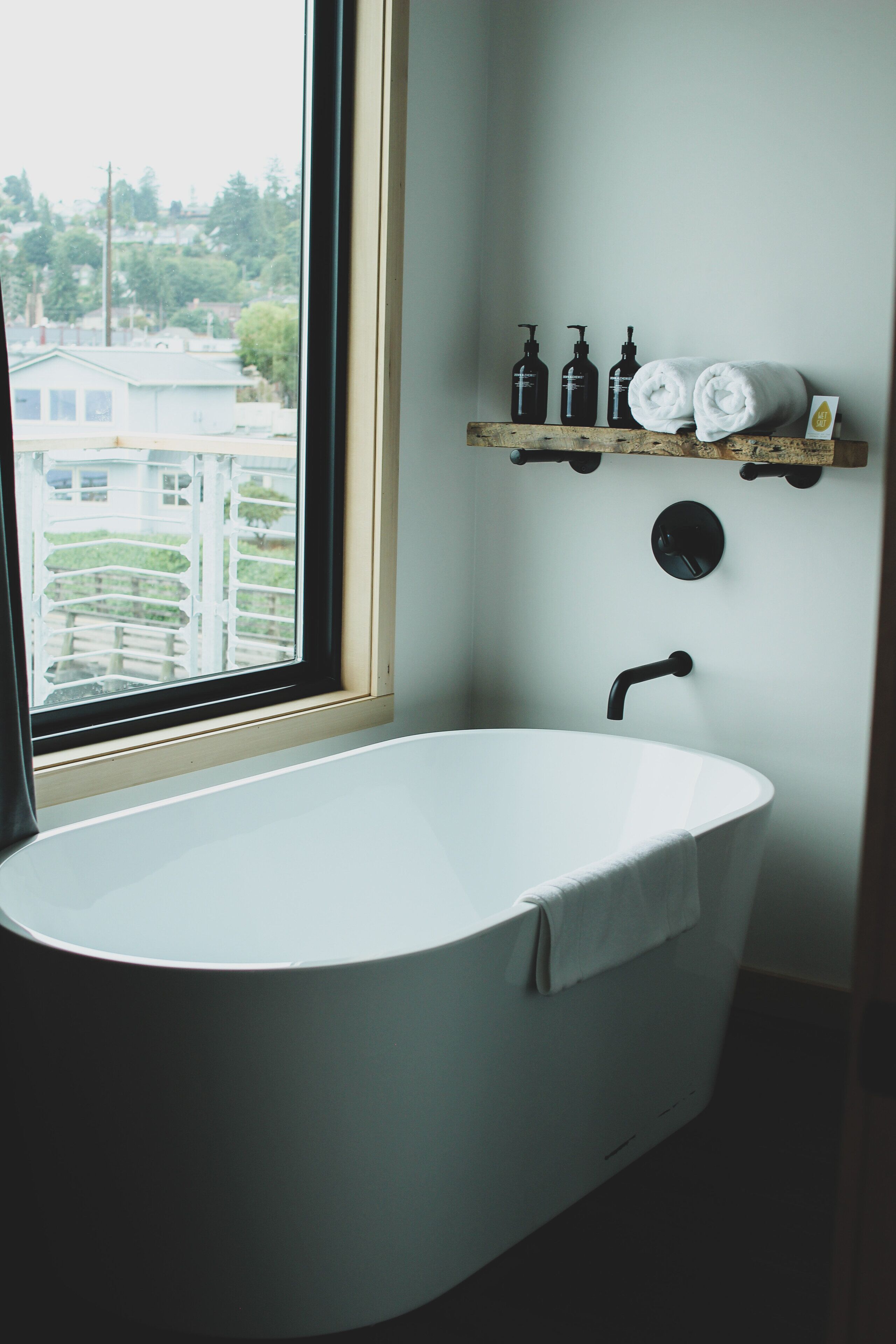 Ein Badezimmer mit einer freistehenden Badewanne, einem Fenster und einem Ablagebereich für Toilettenartikel.