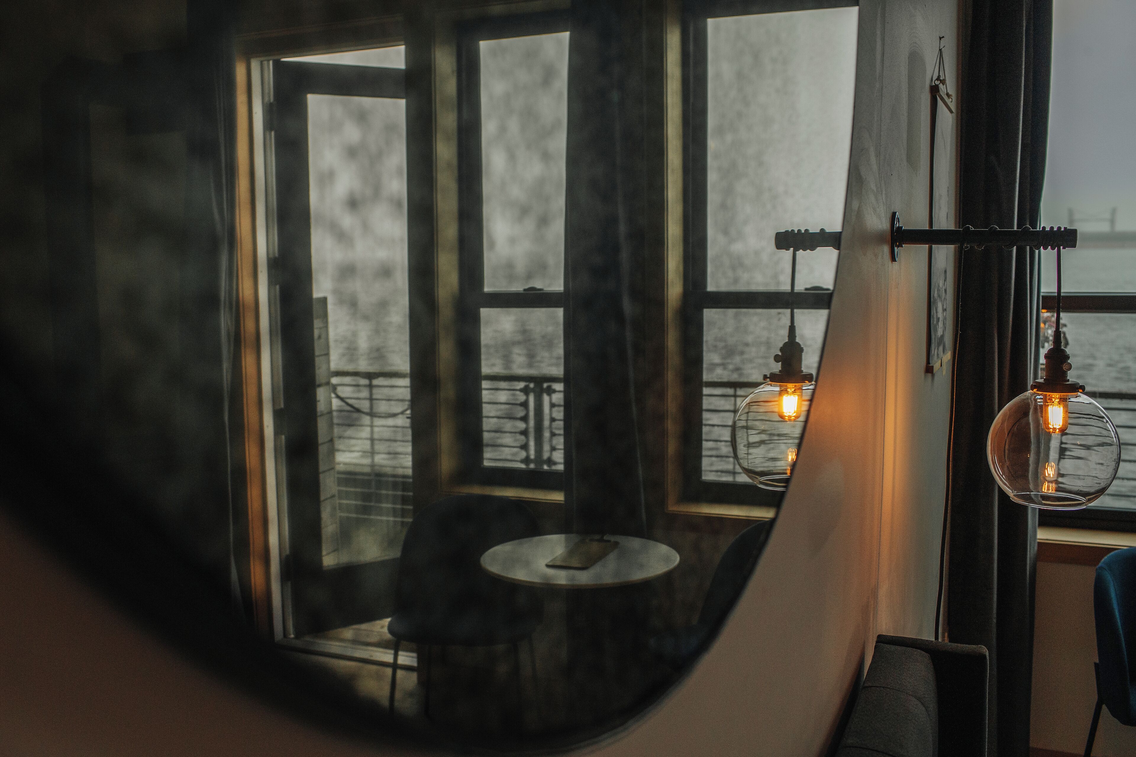 A room with a large window, a table, and two hanging light fixtures.