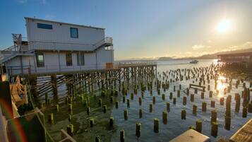 A waterfront building with a dock extending into the water, surrounded by numerous wooden posts.