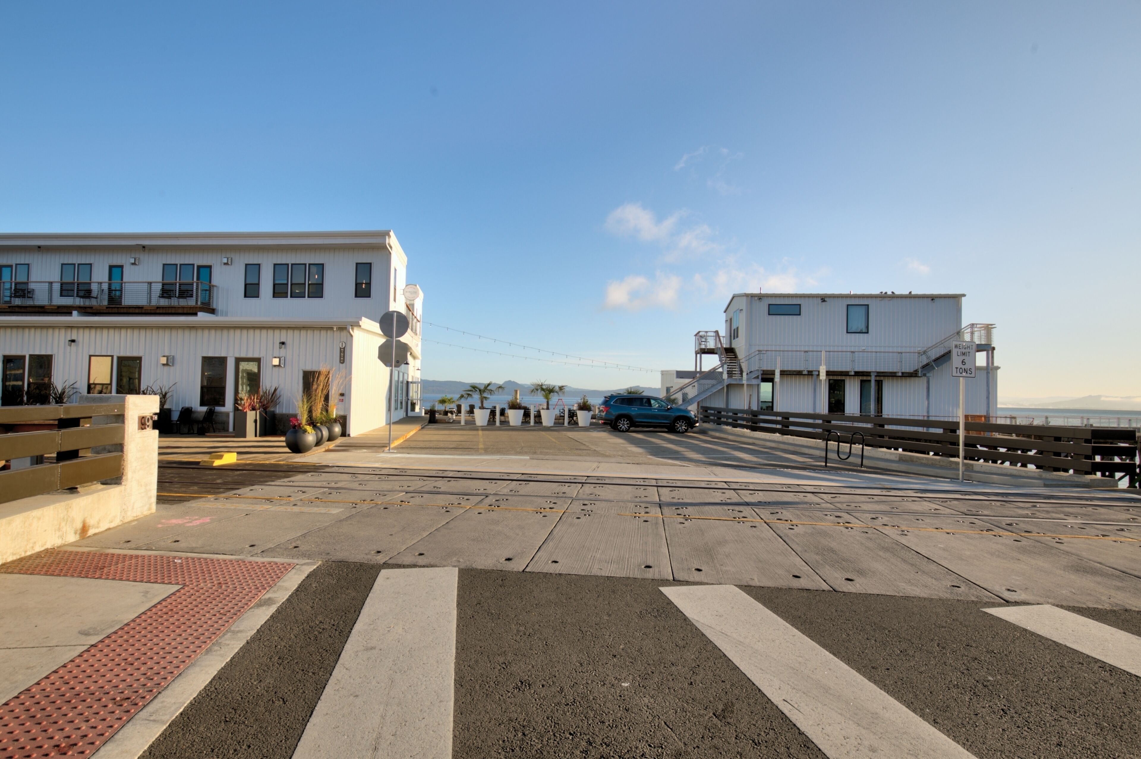 A coastal building with a flat roof, large windows, and a visible staircase leading to an upper level.