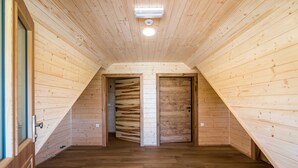 A wooden attic room with a sloped ceiling, two doors, and a visible light fixture.