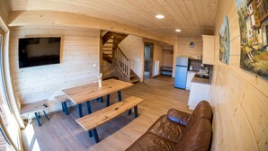 A wooden interior with a sofa, a table, and a staircase.