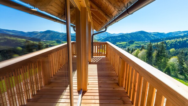A wooden balcony with a view of a mountainous landscape.