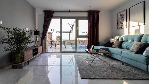Un salon moderne avec un canapé bleu, une table basse et une grande fenêtre avec des rideaux.