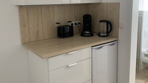 A compact kitchen with white cabinets, a wooden countertop, a coffee maker, and a dishwasher. - LouVi Apartment in Kehl am Rhein (Kehl)