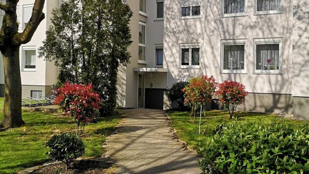A modern apartment building with a central entrance, surrounded by well-maintained gardens and trees. - LouVi Apartment in Kehl am Rhein (Kehl)