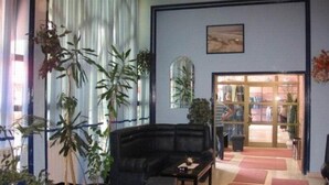 A room with a black sofa, a coffee table, and a large window with curtains. There is a door leading to another room. - Oxa Hotel (Novi Pazar)