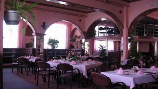 A restaurant with multiple tables and chairs, arched ceilings, and hanging plants. - Oxa Hotel (Novi Pazar)