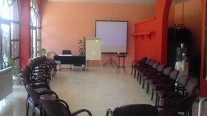 A conference room with a long table, chairs, a projector screen, and a whiteboard. - Oxa Hotel (Novi Pazar)