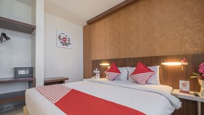 A hotel room with a bed, bedside table, and a small desk with a lamp. - All Nite and Day Makassar (Makassar)