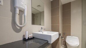 A modern bathroom with a white sink, a mirror, and a toilet. - All Nite and Day Makassar (Makassar)