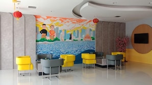 A modern lobby with a mural, seating area, and a reception desk. - All Nite and Day Makassar (Makassar)