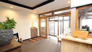 A reception area with a wooden counter, a potted plant, and a sliding glass door leading to a balcony. - Ikoisanso (Karuizawa)