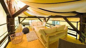 A cozy, tent-like interior with a wooden ceiling, a sofa, a small round table, and a wicker basket. - Ikoisanso (Karuizawa)