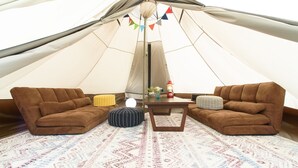 A tent with two brown sofas, a small table, and a patterned rug. - Ikoisanso (Karuizawa)