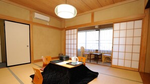 A traditional Japanese room with tatami flooring, a low table with a black quilted cover, a white kettle, and a wooden chair. - Ikoisanso (Karuizawa)