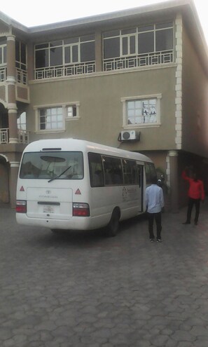A white bus parked in front of a building with multiple windows and balconies.