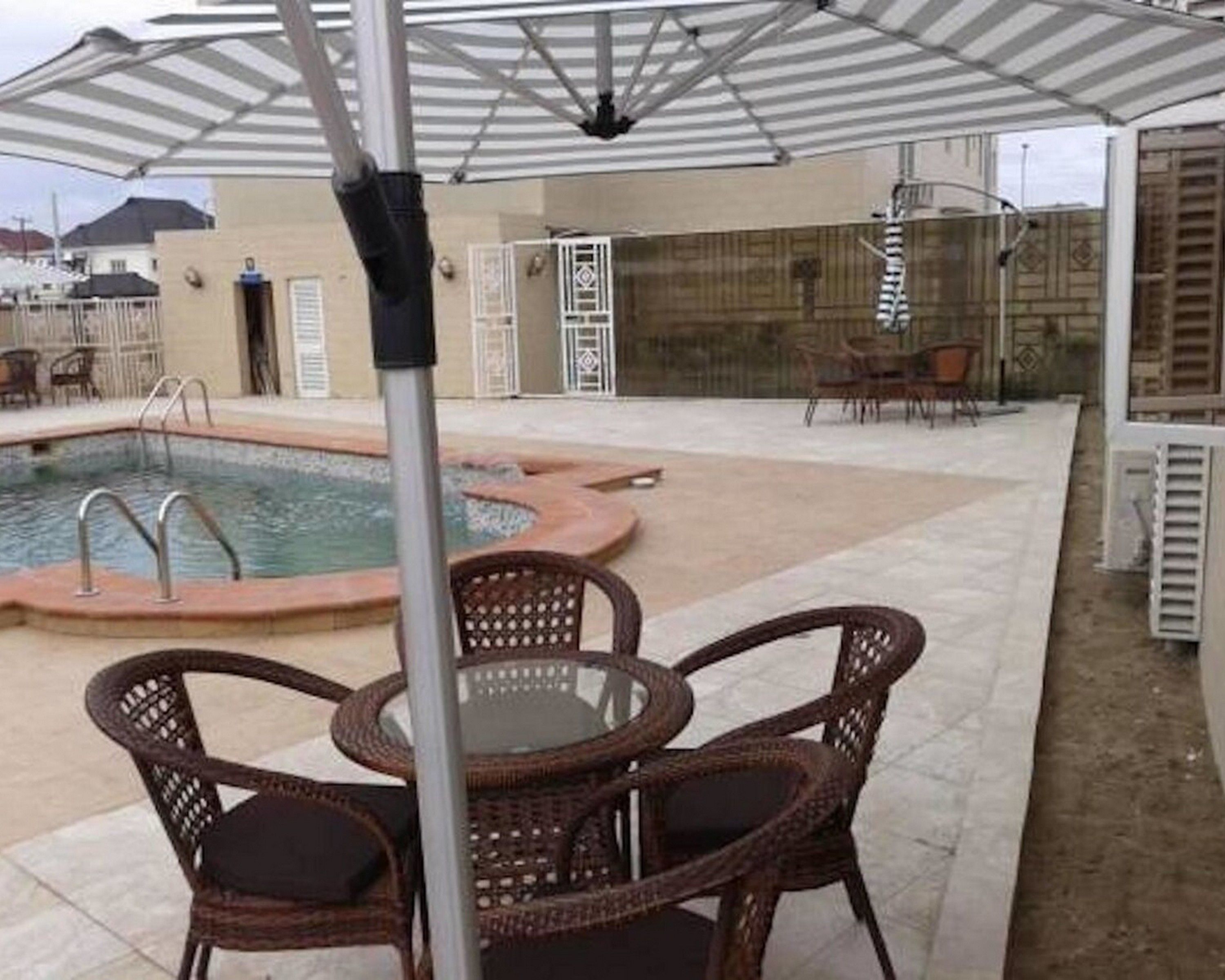 An outdoor pool area with a covered seating area and a poolside chair.
