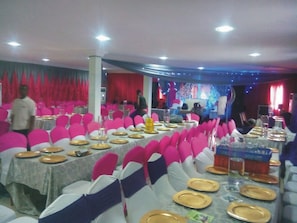 Formal events take place in this elegant banquet hall with tables set with white tablecloths, gold-rimmed plates, and silverware.