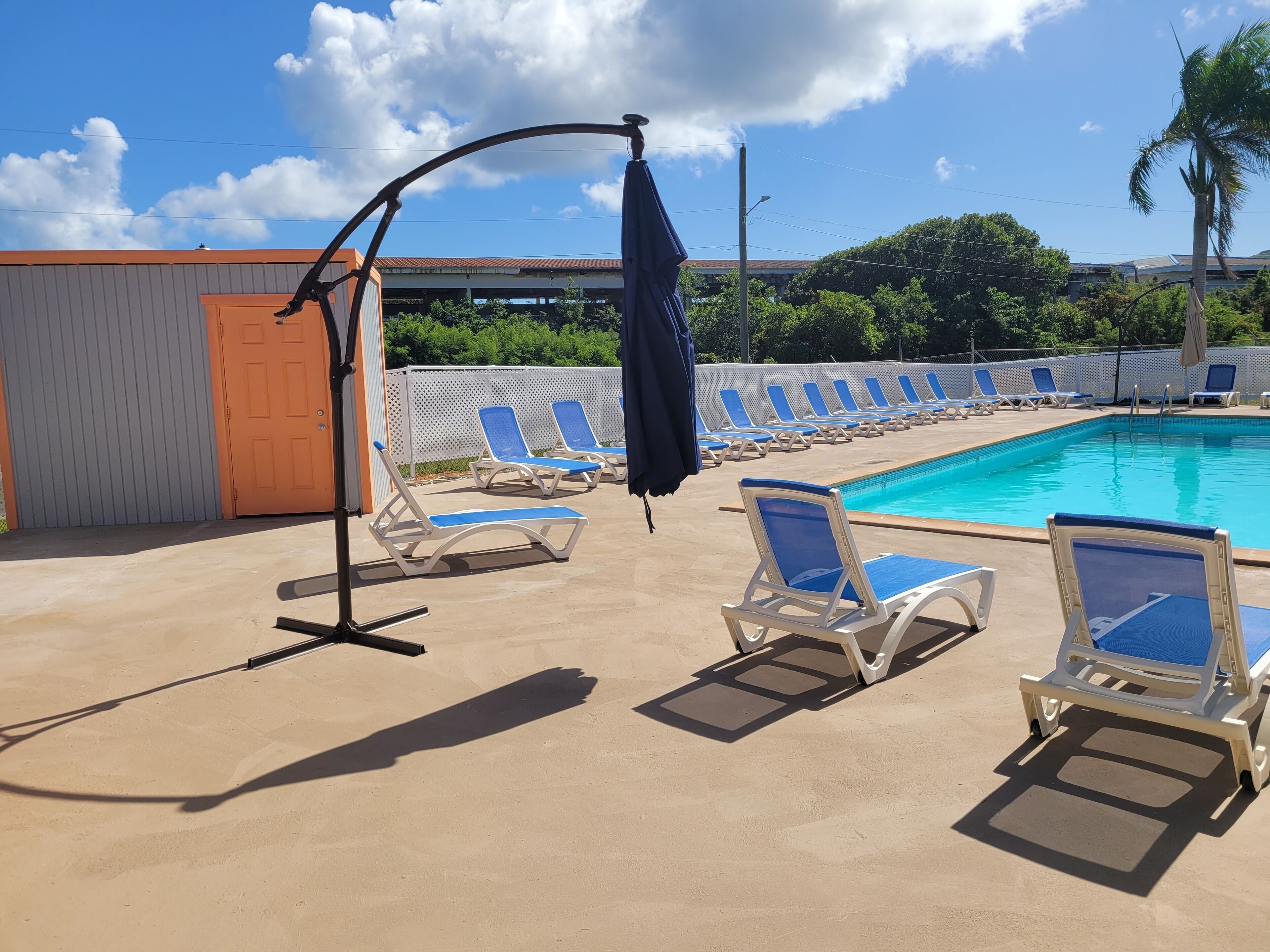 Zona de piscina con sillas de descanso y una sombrilla.